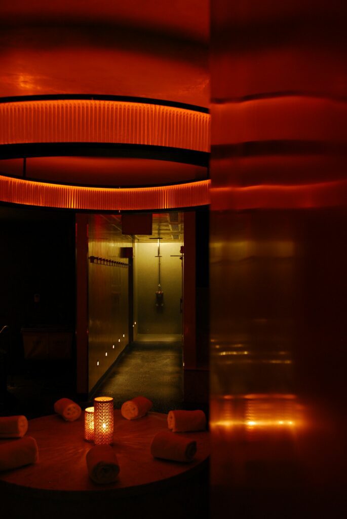 The serene, warmly lit interior of a luxury **Marrakech spa**, showing a relaxation area with rolled towels and candles, perfect for a traditional hammam experience