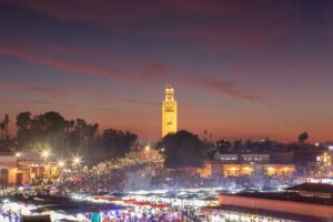 A panoramic view of Djemaa el-Fna square at sunset, with the Koutoubia Mosque in the background, as featured in this Marrakech travel guide